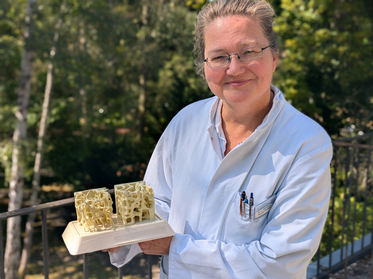 Dr. med. Katja Warnecke steht auf einem Balkon mit einem Modell in der Hand Dr. med. Katja Warnecke steht auf einem Balkon mit einem Modell in der Hand
