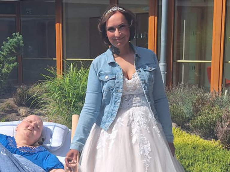Braut Christina im Hochzeitskleid hält im sonnigen Innenhof des Albertinen Hospiz Norderstedt die Hand ihrer im Bett liegenden Mutter. Braut Christina im Hochzeitskleid hält im sonnigen Innenhof des Albertinen Hospiz Norderstedt die Hand ihrer im Bett liegenden Mutter.