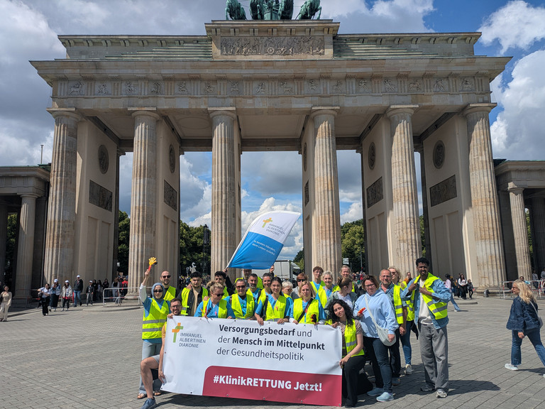 Mitarbeitende mit Banner vor Brandenburger Tor Mitarbeitende mit Banner vor Brandenburger Tor